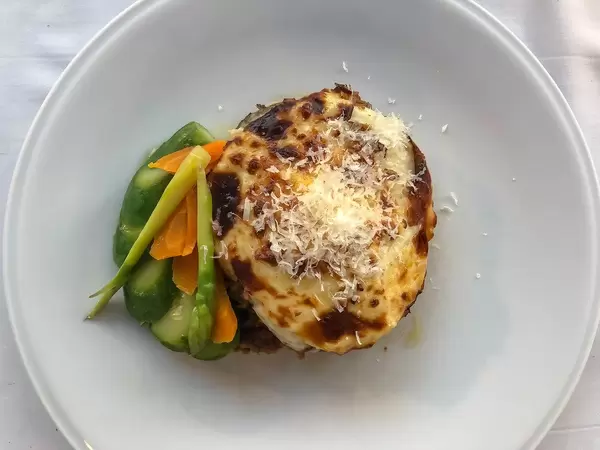 Top view of Greek Moussaka lasagne for lunch, with eggplants, minced meat & healthy side dish, in a mediterranean restaurant