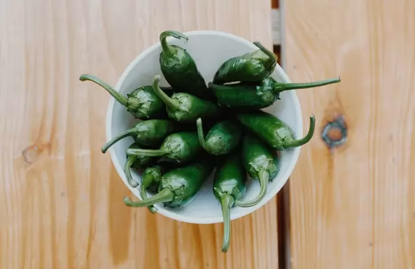 Top view of green spicy peppers on a wooden background