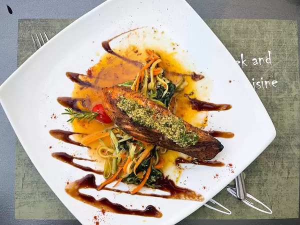 Top view of grilled salmon with veggies, herbs and sauce at Olivo Restaurant on Skopelos