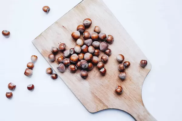 Top view of group of hazelnuts on a wooden board. White background