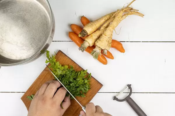 Top view of hand slicing Celery leaves for the soup