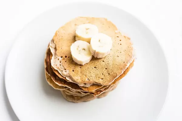 Top view of homemade vegan banana pancakes topped with banana pieces