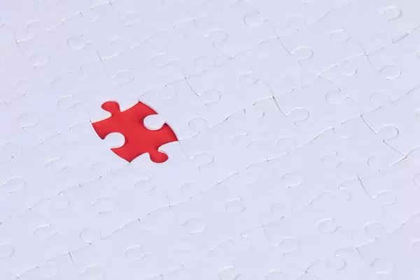 Top view of jigsaw puzzle with one piece left on red background