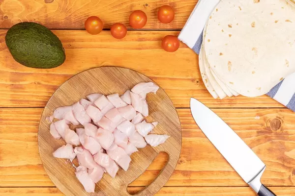 Top view of kithcen table with sliced Chicken Meat and Avocado Cherry Tomato and Tortillas