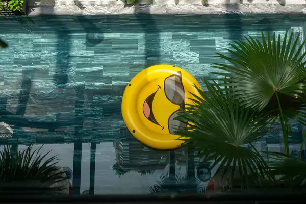Top View of Large Smiley Pool Ring in a Swimming Pool with Plants and Sunlight at Chi House Hotel in Danang, Vietnam