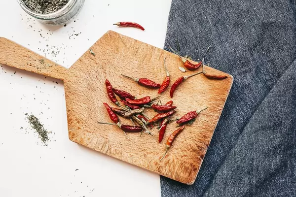 Top view of mini hot dry peppers on wooden board. Kitchen flat lay.