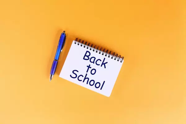Top view of notebook with Back to School text on orange background