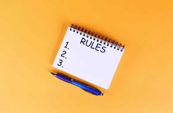 Top view of notebook with rules list on orange background