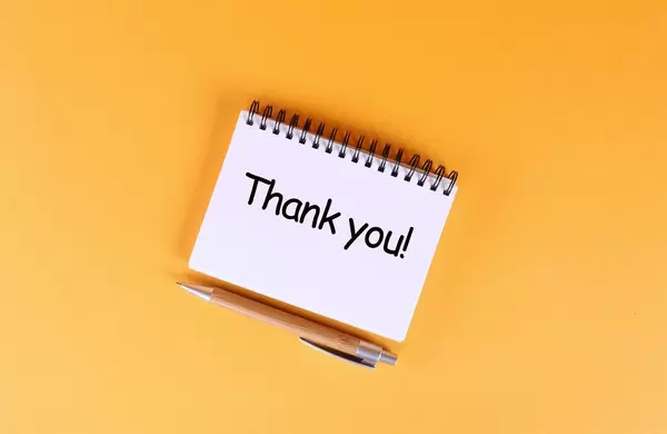 Top view of notebook with Thank you text on orange background