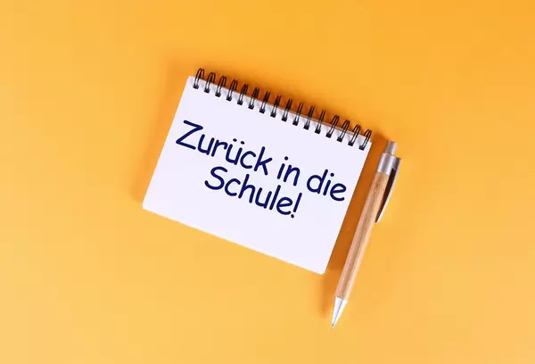 Top view of notebook with Zurück in die Schule text on orange background