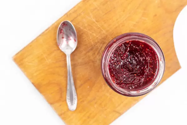 Top view of Raspberry Jam in the jar on the wooden board