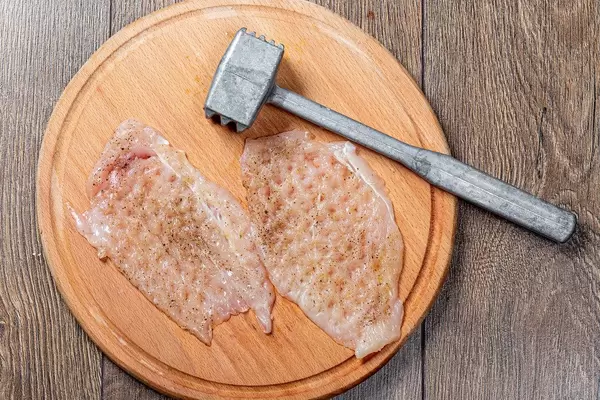 Top view of raw chops and kitchen hammer