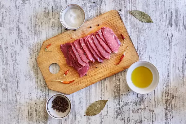 Top view of raw meat cuts with herbs and spices on the cutting board
