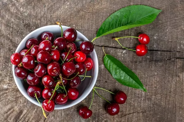 Top view of red cherries with leaves on old grey Board