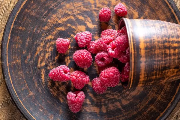 Top view of ripe raspberries on brown plate