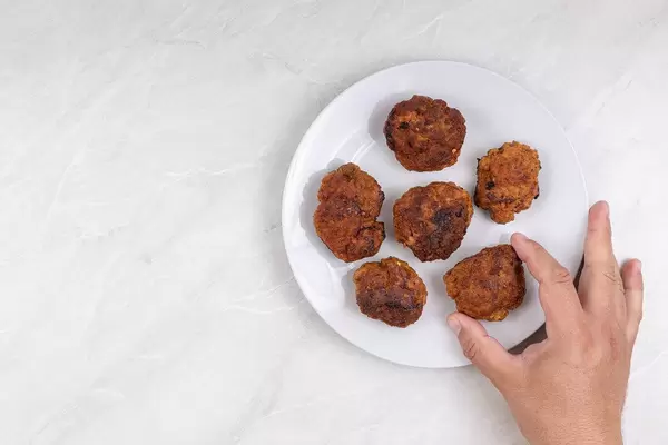 Top view of served Meatballs with hand picking it up
