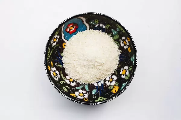 Top view of shredded parmezan cheese in a colorful bowl.