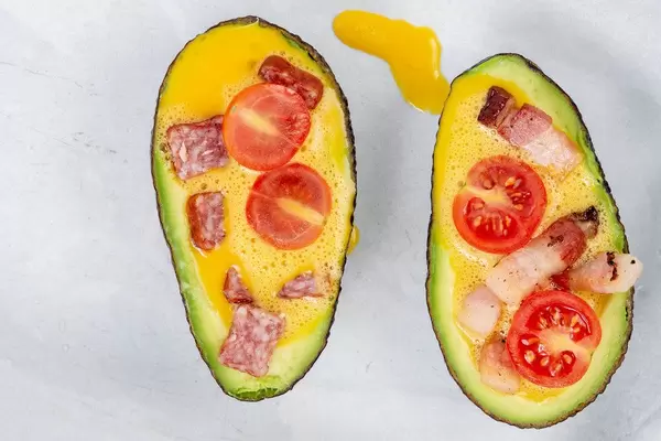 Top view of sliced Avocado with eggs meat and tomato ready for baking (Flip 2019)