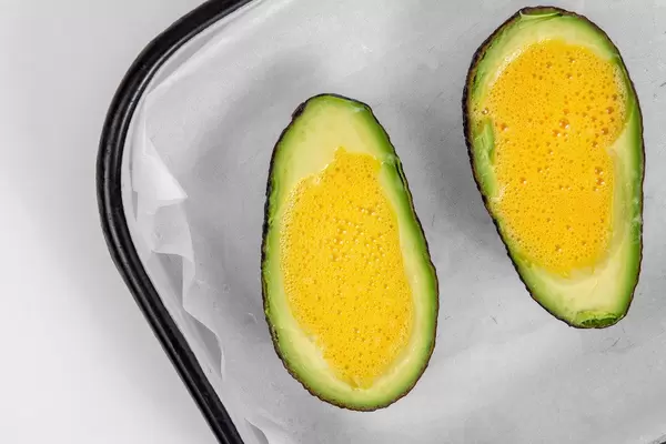 Top view of sliced Avocado with eggs ready for baking