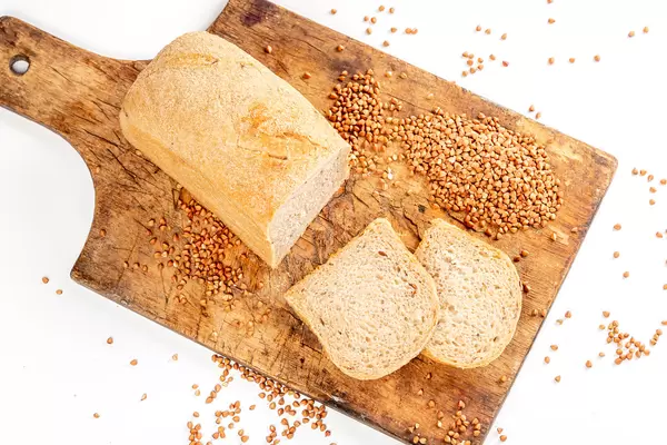Top view of sliced buckwheat bread on wooden kitchen board with sprinkled buckwheat