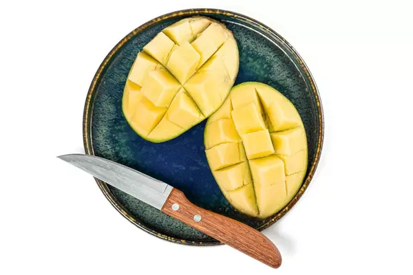 Top view of sliced mango on a plate with a knife