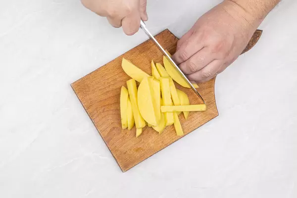 Top view of sliced raw potatoes on the wooden cutting board