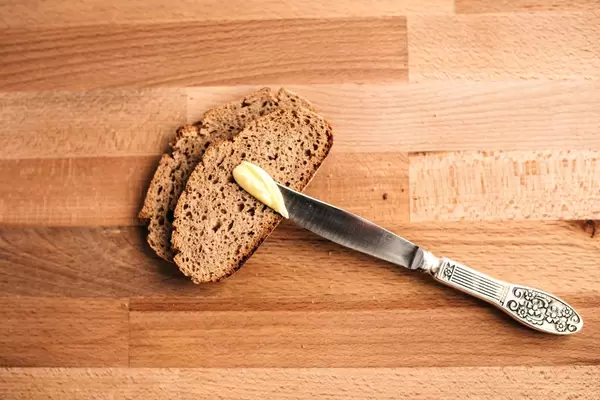 Top view of slices of wholemeal bread with knife and butter on wooden board