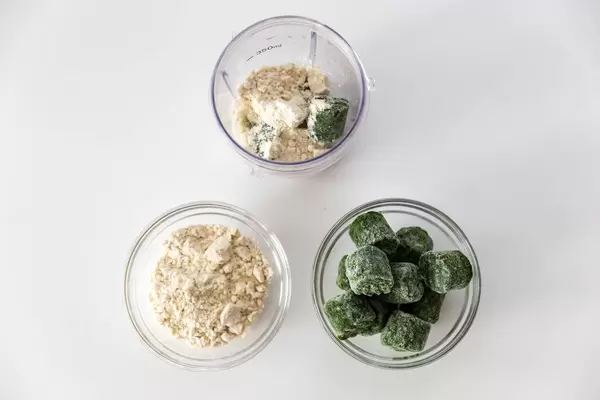 Top view of smoothie ingredients spinach and almond protein powder, with a measuring cup