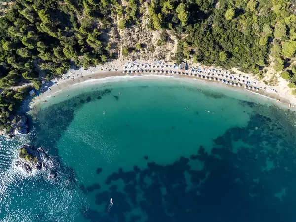 Top view of Stafylos beach with shallow, turquoise waters and wooded hills. Drone photography in Greece