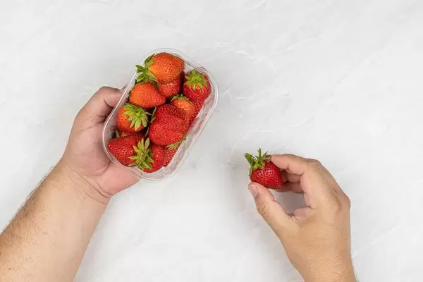 Top view of Strawberries in the plastic market box in the hands