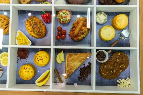 Top view of variety of pastries: fruit tartlets, brown coffee cookies, cinnamon apple turnover  and sausage-pizza