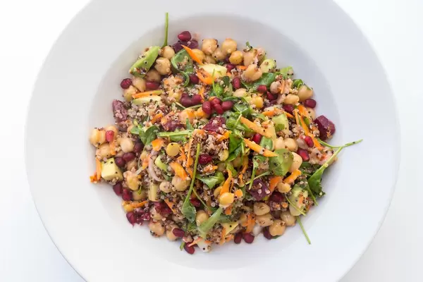 Top view of vegan dish with chickpeas, red beetroot, carrot, avocado, quinoa, spinach and herbs