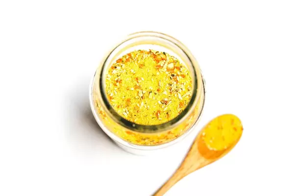 Top view of vegeta seasoning in jar with wooden spoon on white background