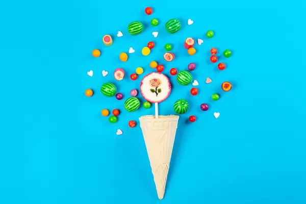 Top view of waffle cone and multicolored candies on blue background