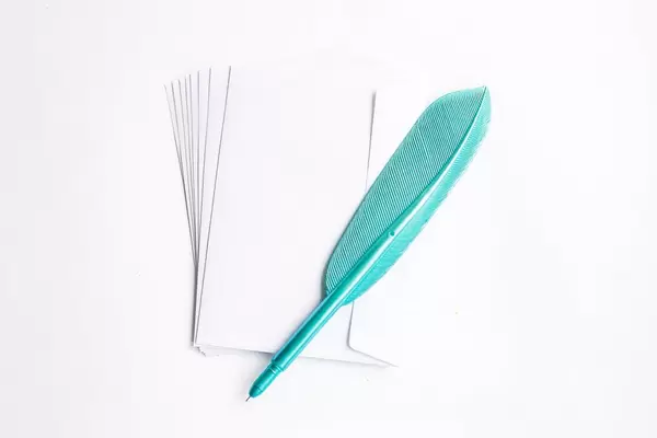Top view of white envelopes with blue plastic feather pen on white background