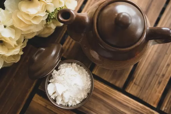 Top view of white powder and teapot on a wooden surface