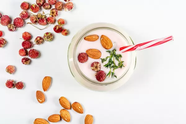 Top view of yogurt with strawberries and almonds on a white background