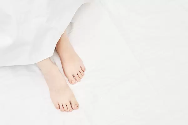 Top view on the sleeping woman legs under blanket