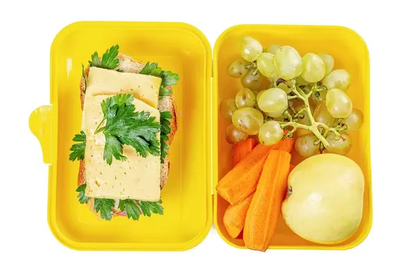 Top view, open lunch box with sandwich, carrots and fruits