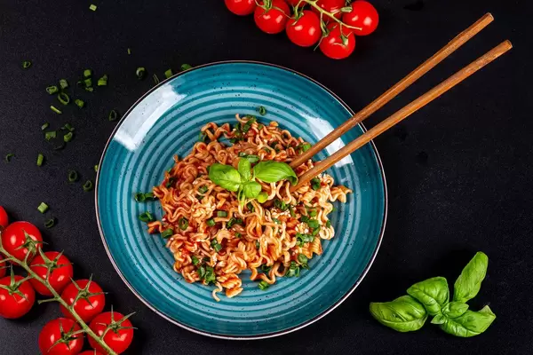 Top view, pasta with sauce, tomatoes and basil on a black background