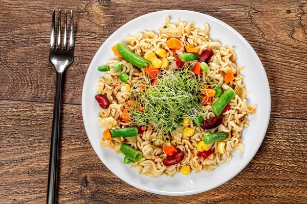 Top view pasta with vegetables on wooden background with fork (Flip 2019)