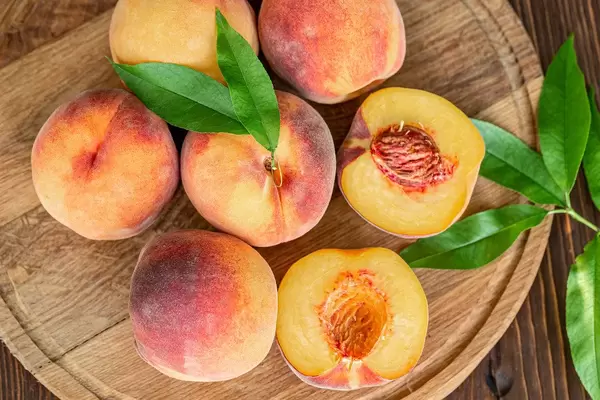 Top view, peaches with leaves on wooden background