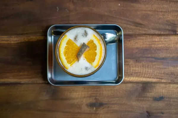 Top View Photo of Cinnamon Orange Iced Tea on a Metal Serving Tray with a Spoon on a Wooden Table