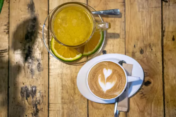 Top View Photo of Cup of Hot Cinnamon-Orange Tea and Cup of Cappuccino on a Wooden Table