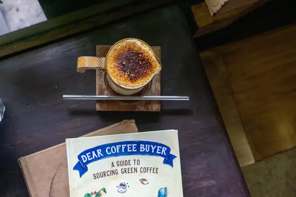 Top View Photo of Dalgona Coffee in Designer Coffee Cup on a Wooden Table with Coffee Guide books at a Cafe