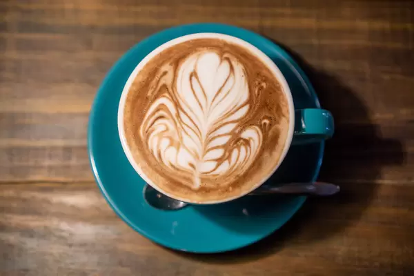 Top View Photo of Hot Cappuccino in Ceramic Cup with Spoon and Saucer on Wooden Table