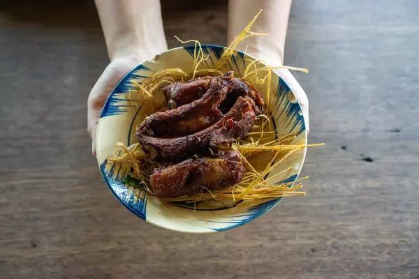 Top View Photo of Person holding a Plate of Fried Pork Ribs on Fried Lemongrass