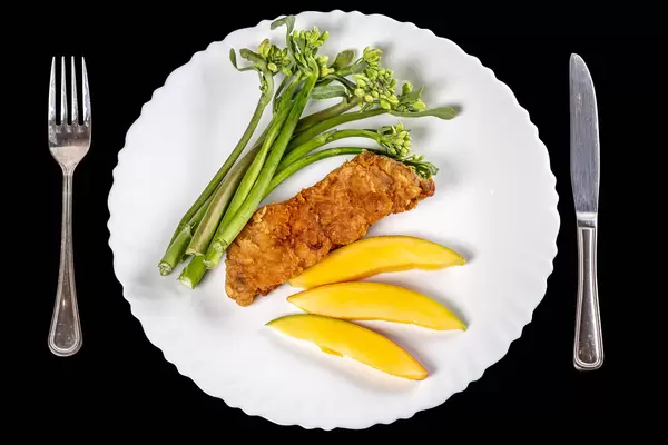 Top view, piece of fried white carp with mango and broccolini