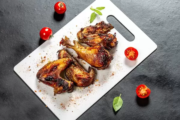 Top view pieces of baked chicken with tomatoes and Basil on a black background (Flip 2019)