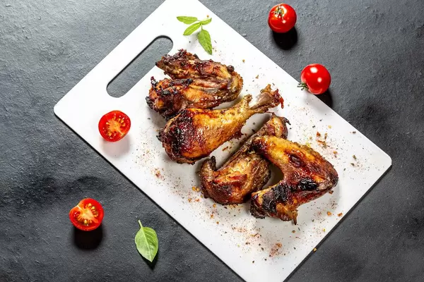 Top view pieces of baked chicken with tomatoes and Basil on a black background
